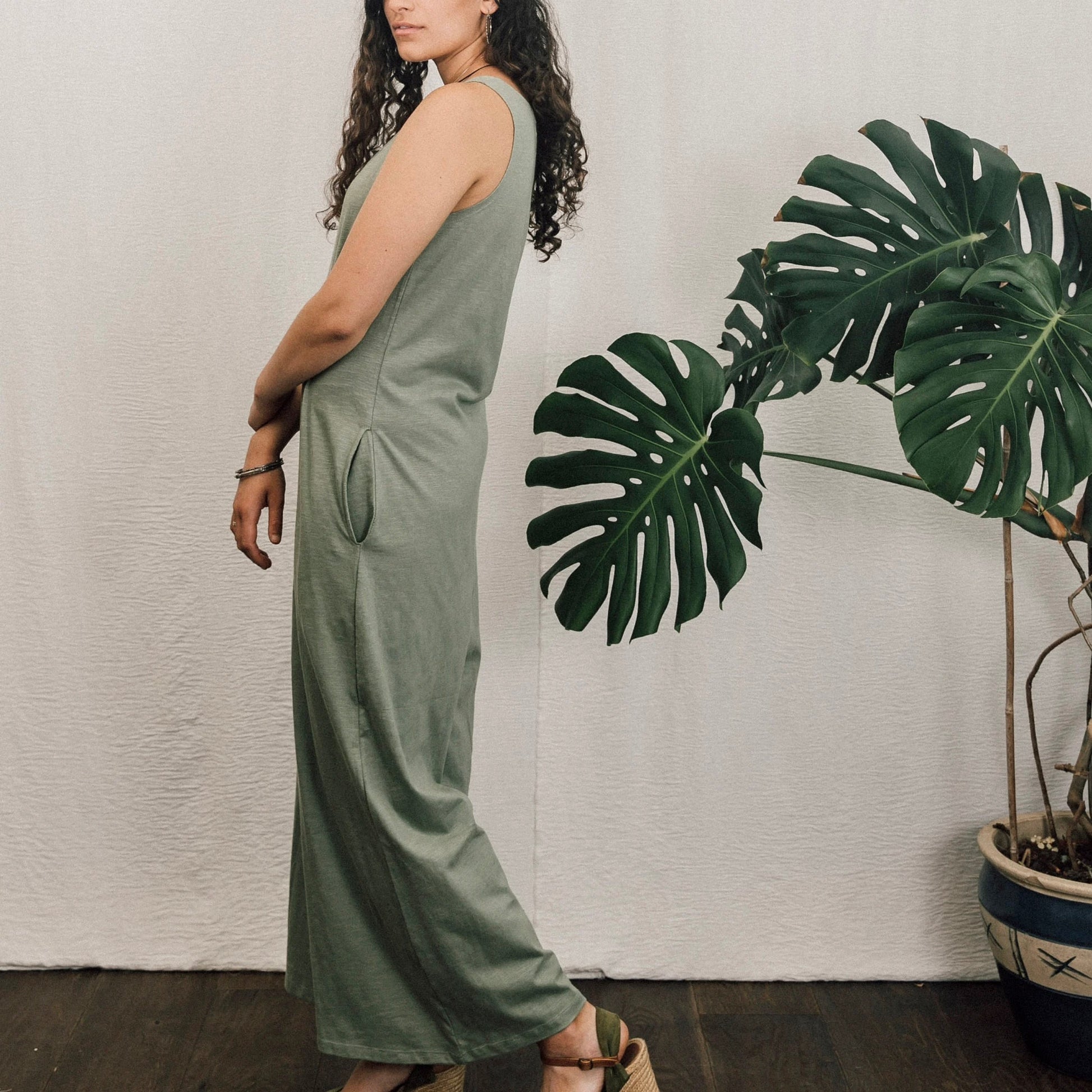 woman wearing green jumpsuit stood by plant